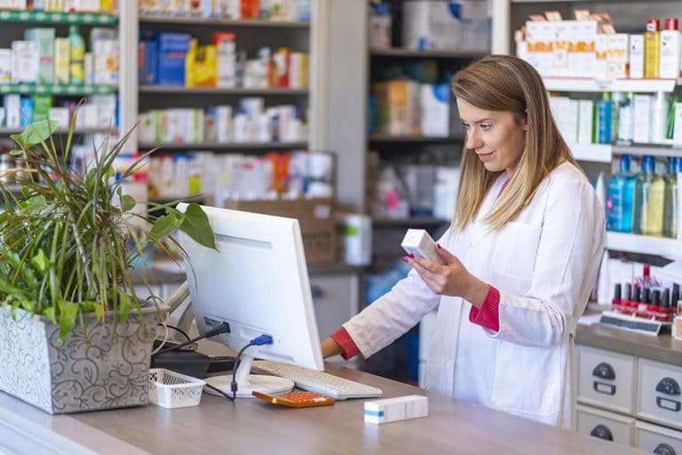 Female pharmacist looking up package on pharmacy computer
