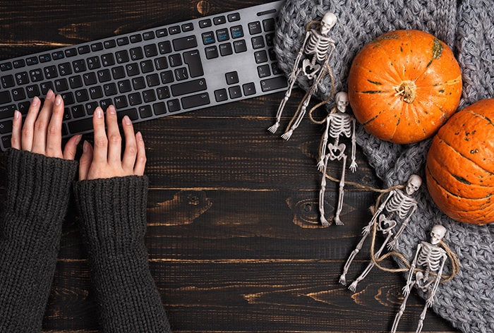 hands typing over keyboard with desk decorated in halloween decor