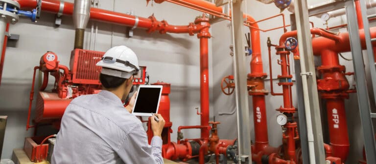 Worker analyzing piping with tablet